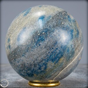 Op de afbeelding: Een blauwe en grijze bol met een gouden metalen standaard. De bol is gemaakt van natuursteen met een gevlekt patroon.