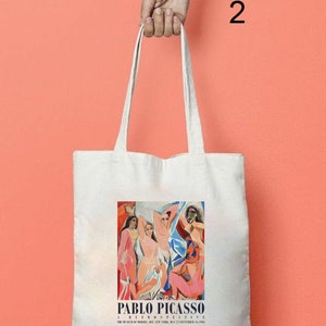 Puede incluir: Bolsa de tela blanca con una pintura colorida de personas de Pablo Picasso. El texto "A Retrospective" y "The Museum of Modern Art, New York, May 27-September 15, 1980" est&aacute; impreso debajo de la pintura.