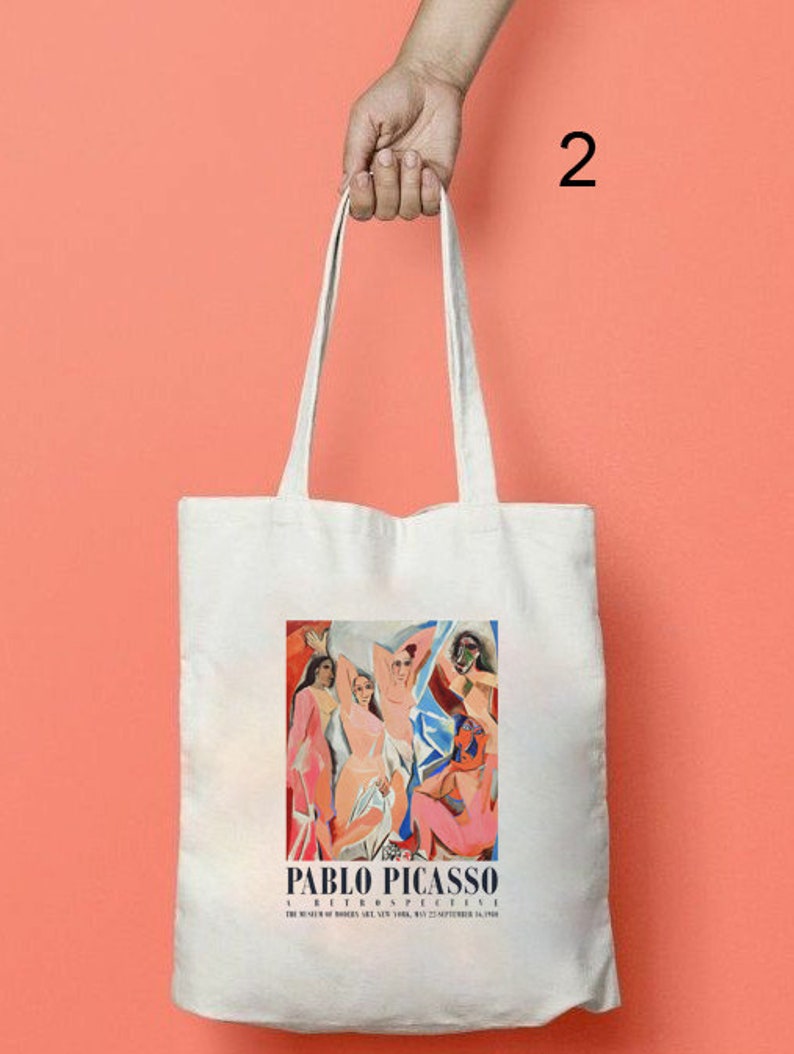 Puede incluir: Bolsa de tela blanca con una pintura colorida de personas de Pablo Picasso. El texto "A Retrospective" y "The Museum of Modern Art, New York, May 27-September 15, 1980" est&aacute; impreso debajo de la pintura.