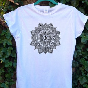 Puede incluir: Camiseta blanca con un diseño de mandala en blanco y negro impreso en la parte delantera.