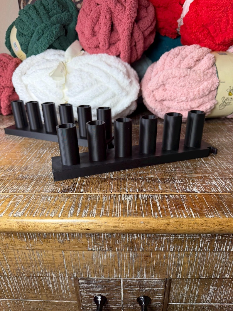 May include: Two black rectangular organizers featuring six vertical cylindrical holders each. These matte black plastic stands are designed with uniform circular openings arranged in a single row, providing a structured base for holding various small items.