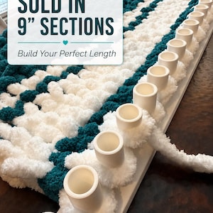May include: A white plastic knitting loom with a row of pegs, featuring thick, soft teal and white yarn loops worked onto the pegs. The text on the image reads: SOLD IN 9" SECTIONS, Build Your Perfect Length. The yarn has a textured, plush appearance.