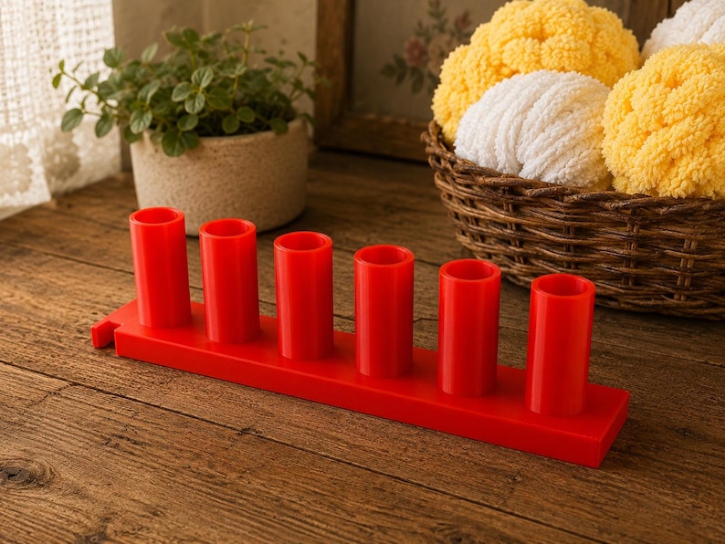 May include: A bright red plastic organizer stand featuring six vertical cylindrical holders arranged in a single row on a rectangular base. The stand has a smooth, solid finish and a small notch on the left side of the base for mounting or attachment.