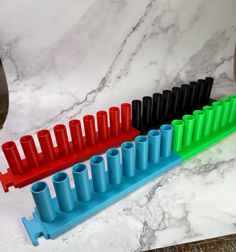 May include: Four modular storage racks in red, black, green, and blue, each featuring a single row of eight vertical cylindrical holders. The racks are designed with interlocking tabs on the ends to connect multiple units together in a line.