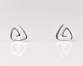 May include: A pair of silver stud earrings with a geometric design. The earrings are shaped like triangles with a spiral pattern inside.