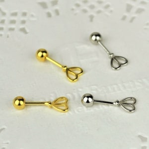 May include: Three pairs of earrings with a heart-shaped design. Two pairs are gold and one pair is silver.