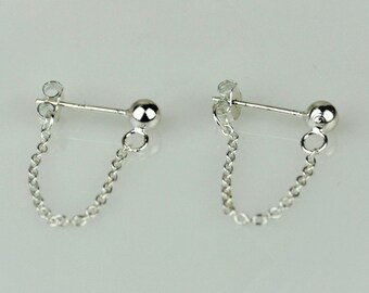 May include: A pair of silver earrings with a small ball at the top and a chain connecting the two balls.