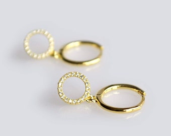 以下が含まれることがあります： 金色のフープピアス。それぞれのフープから小さなパヴェダイヤモンドの円がぶら下がっている。
