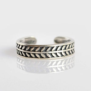 May include: A silver toe ring with a leaf design.