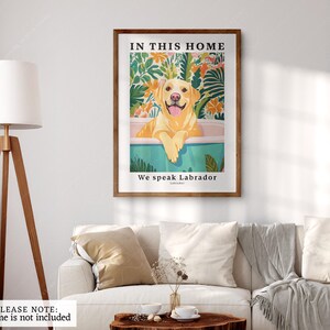 May include: A framed print with a yellow Labrador Retriever sitting in a bathtub. The print has a tropical background and the text "In this home we speak Labrador" at the bottom.
