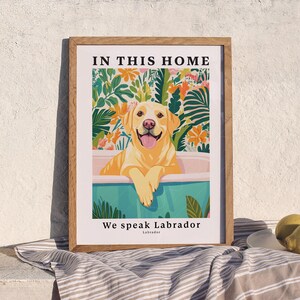 May include: A framed print with a yellow Labrador Retriever in a blue bathtub surrounded by tropical plants. The text "In this home we speak Labrador" is printed below the image.