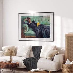 Puede incluir: Una pintura de una mujer con un vestido negro reclinada en un sof&aacute; de terciopelo verde, sosteniendo un libro amarillo. La pintura est&aacute; enmarcada en negro y se exhibe en una pared blanca.