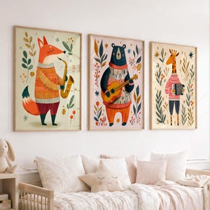 May include: Three framed wall art prints featuring anthropomorphic animals playing musical instruments. A fox plays a saxophone, a bear plays an acoustic guitar, and a giraffe plays an accordion. Each animal wears a patterned sweater and is surrounded by foliage.