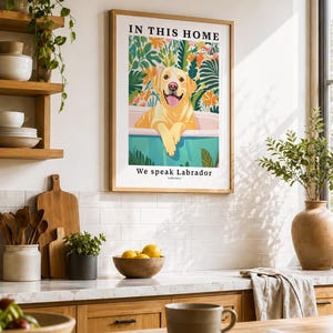 May include: A framed wall art print featuring a yellow Labrador retriever sitting in a bathtub surrounded by colorful tropical foliage. The text at the top reads IN THIS HOME and the text at the bottom reads We speak Labrador and Labrador.