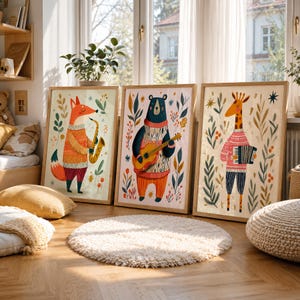 May include: Three framed wall art prints featuring anthropomorphic animals playing musical instruments. A fox plays a saxophone, a bear plays a guitar, and a giraffe plays an accordion. Each animal wears a patterned sweater amidst botanical foliage.