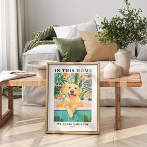 May include: A framed print with a yellow Labrador Retriever sitting in a bathtub surrounded by tropical plants. The text on the print reads "In this home we speak Labrador".