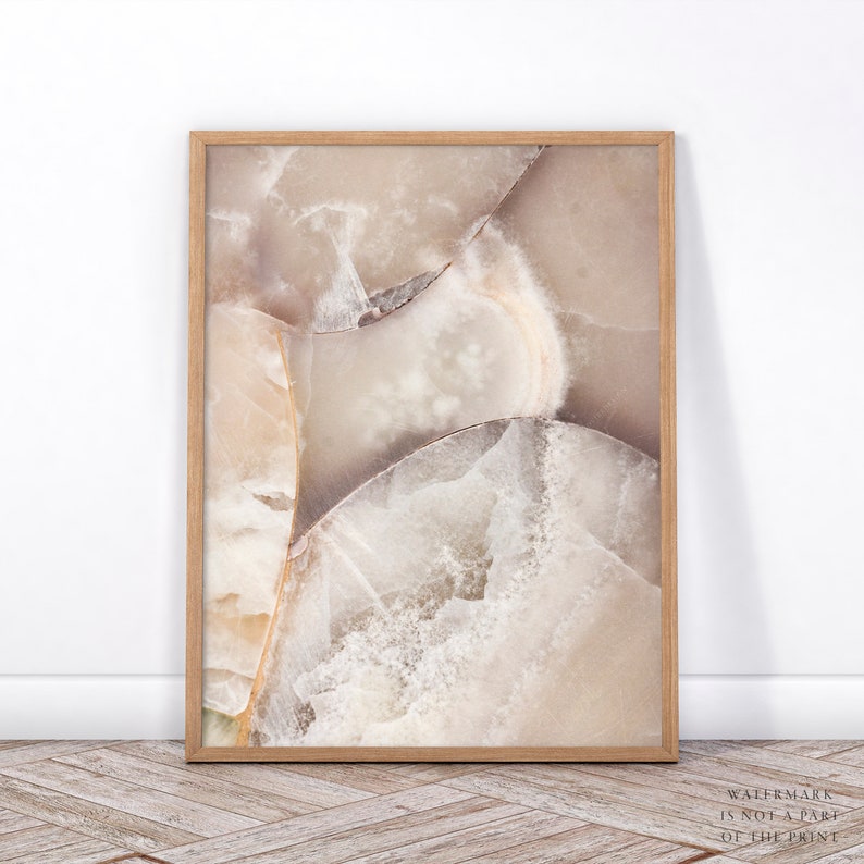 Puede incluir: Una impresi&oacute;n enmarcada que presenta un primer plano de una piedra pulida con un dise&ntilde;o natural y abstracto. La obra de arte muestra una mezcla de tonos beige, crema y marr&oacute;n claro, con vetas y estructuras cristalinas visibles. El marco de madera a&ntilde;ade calidez.