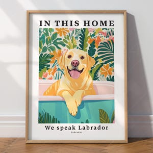 May include: A framed print with a yellow Labrador Retriever sitting in a bathtub surrounded by tropical plants. The text "In this home we speak Labrador" is printed below the image.