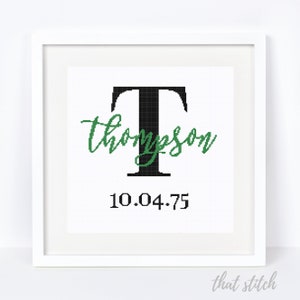 May include: A white framed cross-stitch design featuring a black letter T with the name "Thompson" in green cursive script and the date "10.04.75" below.