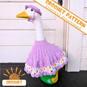 May include: A ceramic goose statue wearing a crocheted lavender dress and matching bonnet. The dress features a white daisy trim. The goose has a yellow beak and green feet. Text on the image reads "CROCHET PATTERN Instant Download" and "CROCHET IN THE SUNSHINE".