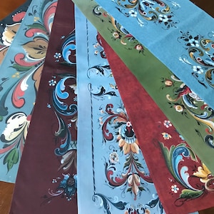 Könnte beinhalten: Eine Sammlung dekorativer Stoffstücke mit kunstvollen Blumen- und Rankenmustern. Die Farbpalette umfasst Blau-, Rot-, Grün- und Brauntöne. Die Muster sind handbemalt mit aufwendigen Details und zeigen eine Vintage-Ästhetik.