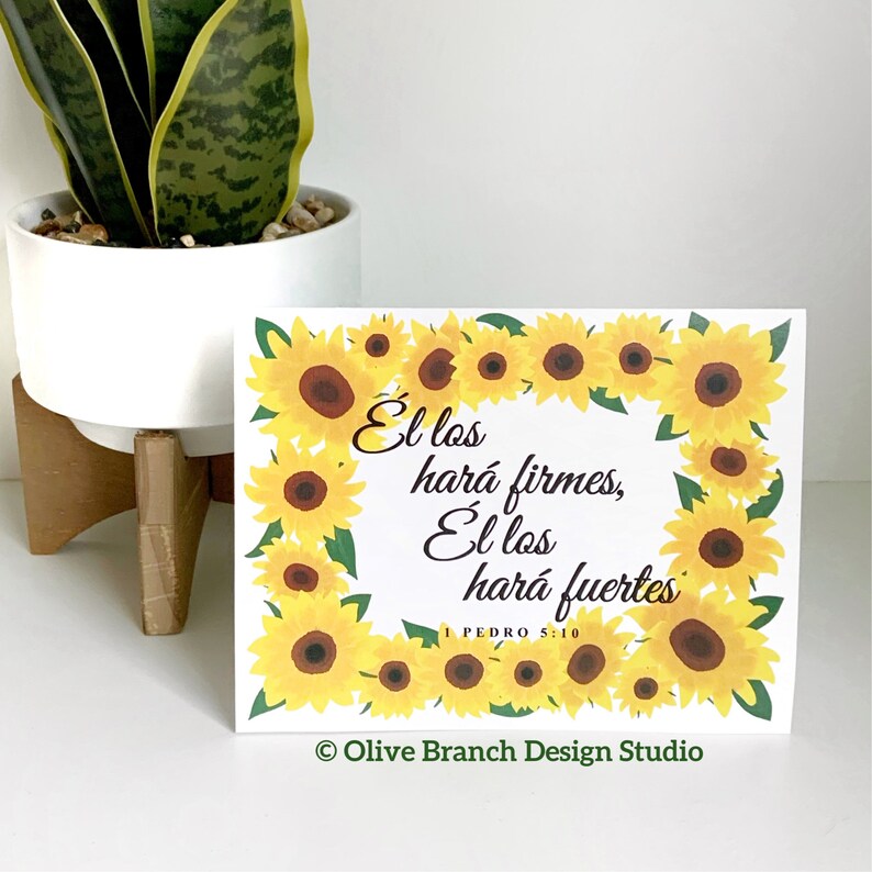May include: A white card with a sunflower border and the text "El los har&aacute; firmes, El los har&aacute; fuertes 1 PEDRO 5:10" in black. The card also has the text "Olive Branch Design Studio" in green at the bottom.