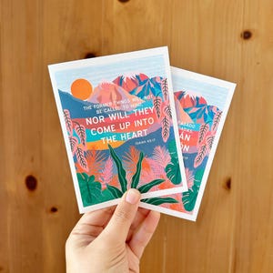 May include: Two colourful cards with a mountain landscape and tropical plants. The text on the cards reads "The former things will not be called to mind, nor will they come up into the heart. Isaiah 65:17"