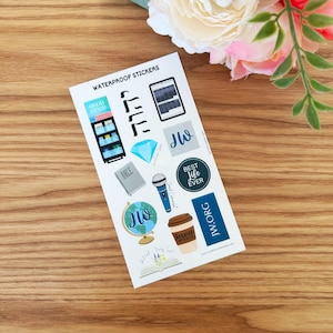 May include: A sheet of waterproof stickers featuring various illustrations and text. Designs include a bookshelf, a diamond, a microphone, a coffee cup, a globe, and the text "GOOD NEWS!", "BEST LIFE EVER", and "JW.ORG".