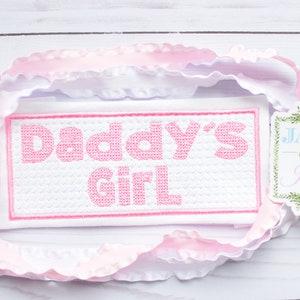 May include: White fabric with pink embroidery that reads "Daddy's Girl". A small white tag with green trim reads "Jax & Jane".
