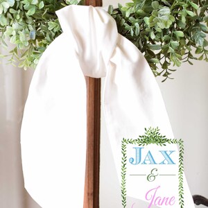 May include: White fabric sash with a green leafy border and the text "Jax & Jane" in blue and pink lettering.