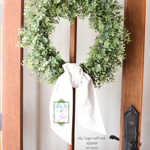 May include: A green wreath with a white ribbon and a sign that says "JAX & Jane" hanging on a wooden door.
