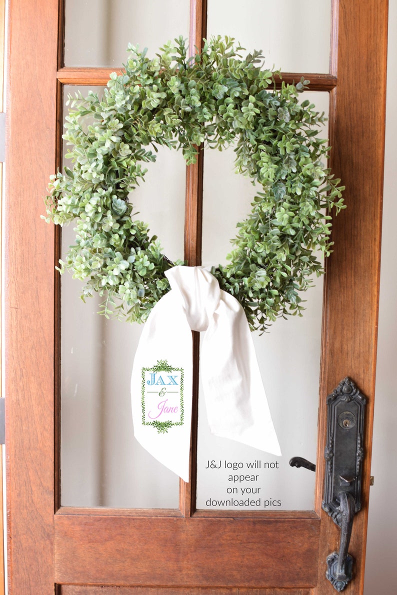 May include: A green wreath with a white ribbon and a sign that says "JAX & Jane" hanging on a wooden door.