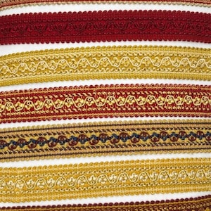 Könnte beinhalten: Eine Auswahl an dekorativen Zierbändern in Gold, Rot und Braun. Die Bänder weisen detaillierte Muster und Texturen auf, ideal für Bastelarbeiten und Verzierungen. Das Bild zeigt eine Reihe von Designs, von gewellten Kanten bis hin zu aufwendigen Webdetails.