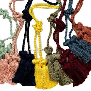 May include: Assortment of colorful tassel cords with various colors including green, pink, navy blue, yellow, olive green, and burgundy. The cords are made of twisted rope and have a tassel at the end.