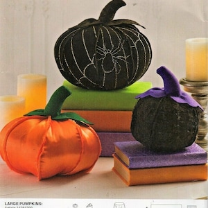 May include: A Simplicity sewing pattern for making three Halloween pumpkins. The pattern includes instructions for making a large black pumpkin with a spider web design, a large orange pumpkin, and a small black pumpkin with a purple stem. The pattern also includes instructions for making a table runner, a table skirt, and other decorative items.