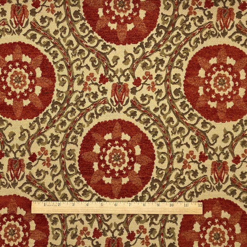 May include: Red, green, and cream patterned fabric with a repeating floral design. The fabric has a textured surface.