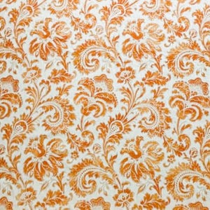 May include: A repeating pattern of orange floral and paisley designs on a white background. The pattern features detailed, stylized flowers and swirling paisley elements, creating a vintage or classic aesthetic. The color palette is warm and inviting.