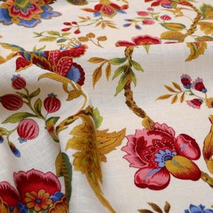 May include: White fabric with a floral pattern featuring red, pink, blue, and yellow flowers. The flowers are arranged on a vine with green leaves.