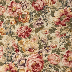 May include: A close-up of a floral fabric featuring a dense pattern of large, colorful flowers. The blooms are in shades of pink, red, yellow, and purple, with green leaves and stems. The background is a light beige color, creating a vintage aesthetic.