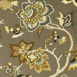 May include: A fabric featuring a repeating botanical pattern on a taupe background. The design includes large stylized flowers and leaves in shades of mustard yellow, dark green, and cream, connected by thin, light-colored, branching stems.