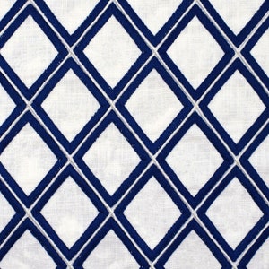 May include: White fabric with a repeating diamond pattern embroidered in navy blue thread. The diamonds are outlined with a thin white thread, creating a textured, geometric design. The fabric appears to be linen or a similar natural fiber.