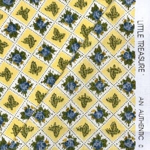 May include: Yellow fabric with a repeating pattern of blue floral and green leaf motifs within a diamond grid. The fabric has the text "LITTLE TREASURE. AN AUTHENTIC" printed on the right side.