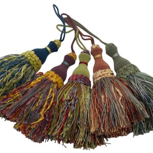 Puede incluir: Cuatro lazos de cortina con borlas de colores con una mezcla de hilos verdes, azules, rojos y amarillos. Las borlas están hechas de tejido tejido y tienen un nudo decorativo en la parte superior.