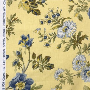 Peut inclure: Tissu floral avec un fond jaune et un motif de fleurs bleues et blanches avec des feuilles vertes. Le tissu porte l'inscription "FOR COVINGTON FAST COLORS SCREEN PRINTED PROTECTED WITH COV" sur le côté.