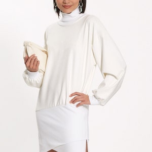 May include: White turtleneck dress with a long sleeve and a fitted skirt. The dress has a gathered waist and a slightly asymmetrical hemline.