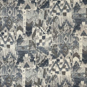 May include: Textile fabric with a geometric pattern in shades of blue, gray, and off-white. The design features abstract shapes and textures, creating a visually complex and artistic look. The fabric appears to be woven.