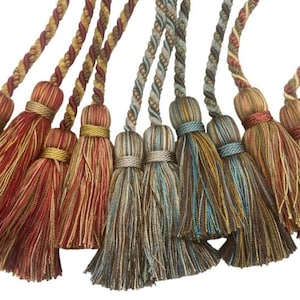 Puede incluir: Un conjunto de ocho lazos para cortinas con borlas en varios colores y patrones, incluyendo rojo, dorado, marrón y azul. Las borlas están hechas de un tejido suave y tejido y tienen una larga franja fluida.