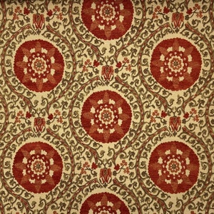 May include: A beige fabric with a repeating pattern of red and orange floral medallions. The fabric has a subtle texture and a vintage aesthetic.