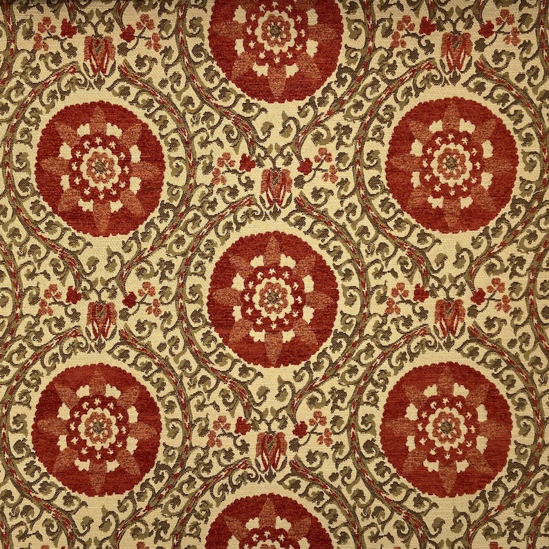 May include: A beige fabric with a repeating pattern of red and orange floral medallions. The fabric has a subtle texture and a vintage aesthetic.