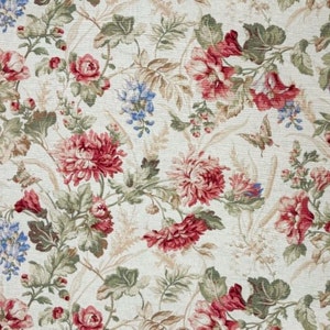 Könnte beinhalten: Ein cremefarbener Stoff mit einem Blumenmuster. Das Muster zeigt rote, rosa und blaue Blumen mit grünen Blättern. Der Stoff hat eine subtile Textur.